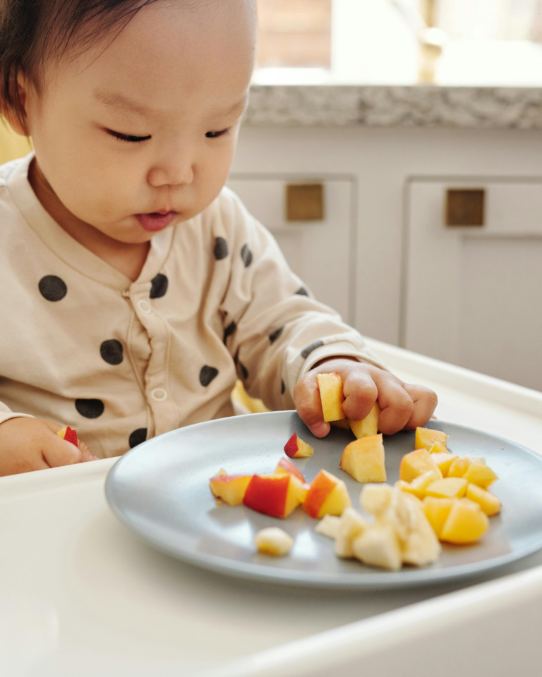 Baby eating fruit from a plate